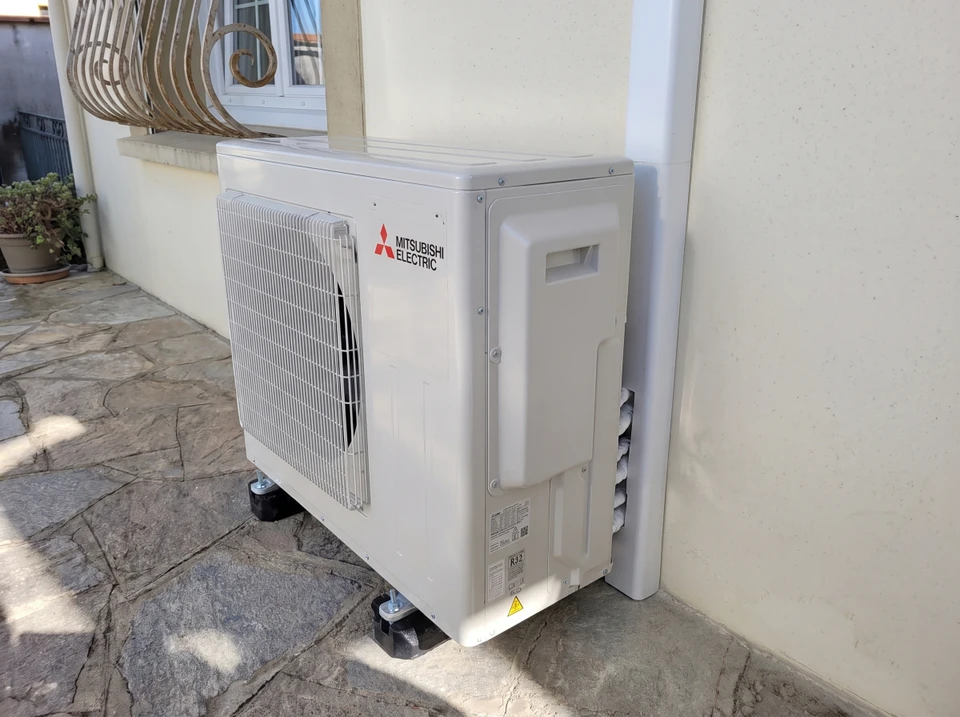 Installateur professionnel agenouillé dans une pièce blanche posant un système de chauffage au sol